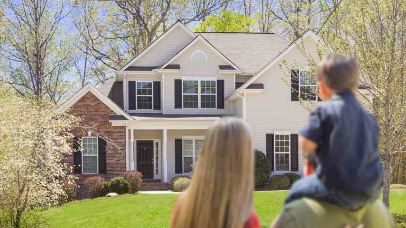 Mixed Race Young Family Looking At Beautiful New Home.